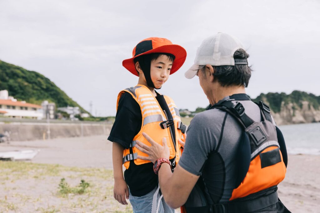 子どもにライフジャケットを着せている画像