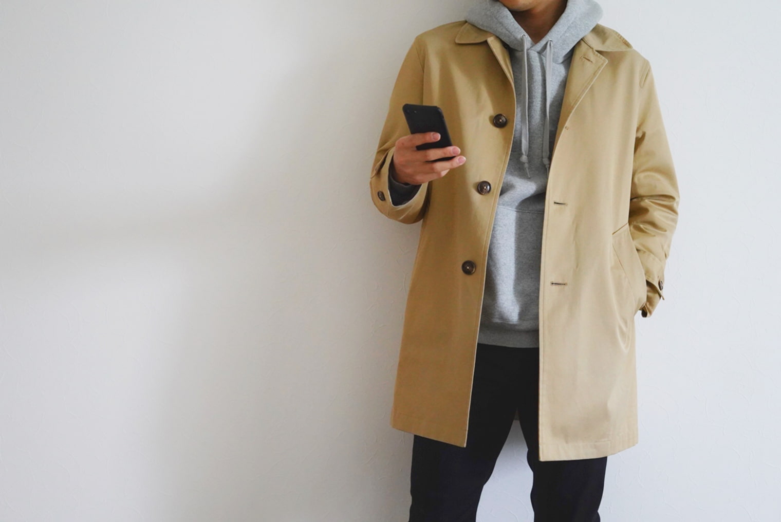 薄手コートとパーカーを着る男性