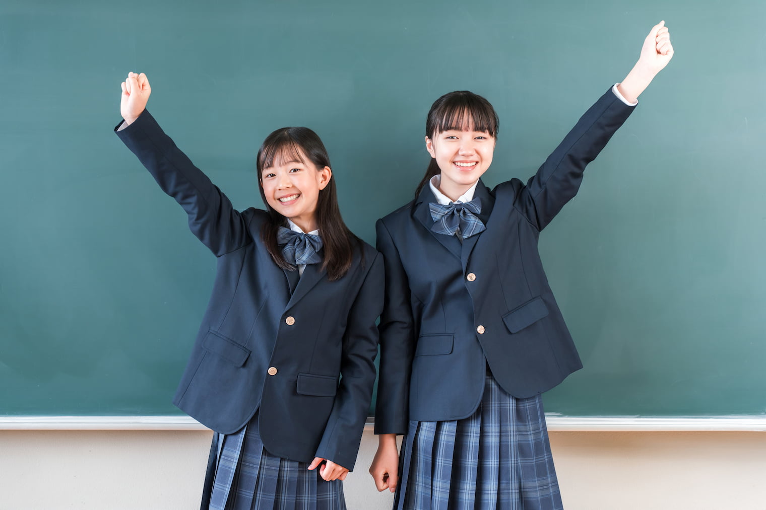 黒板の前でガッツポーズをする女子高生たち