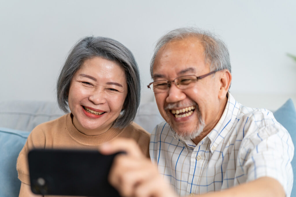 携帯の画面を見て笑う熟年夫婦